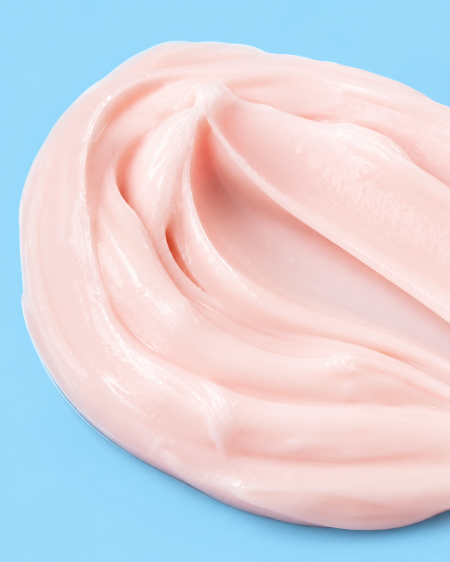 Close-up of Veloura Peptide Anti-Aging Serum silky pink texture on blue background